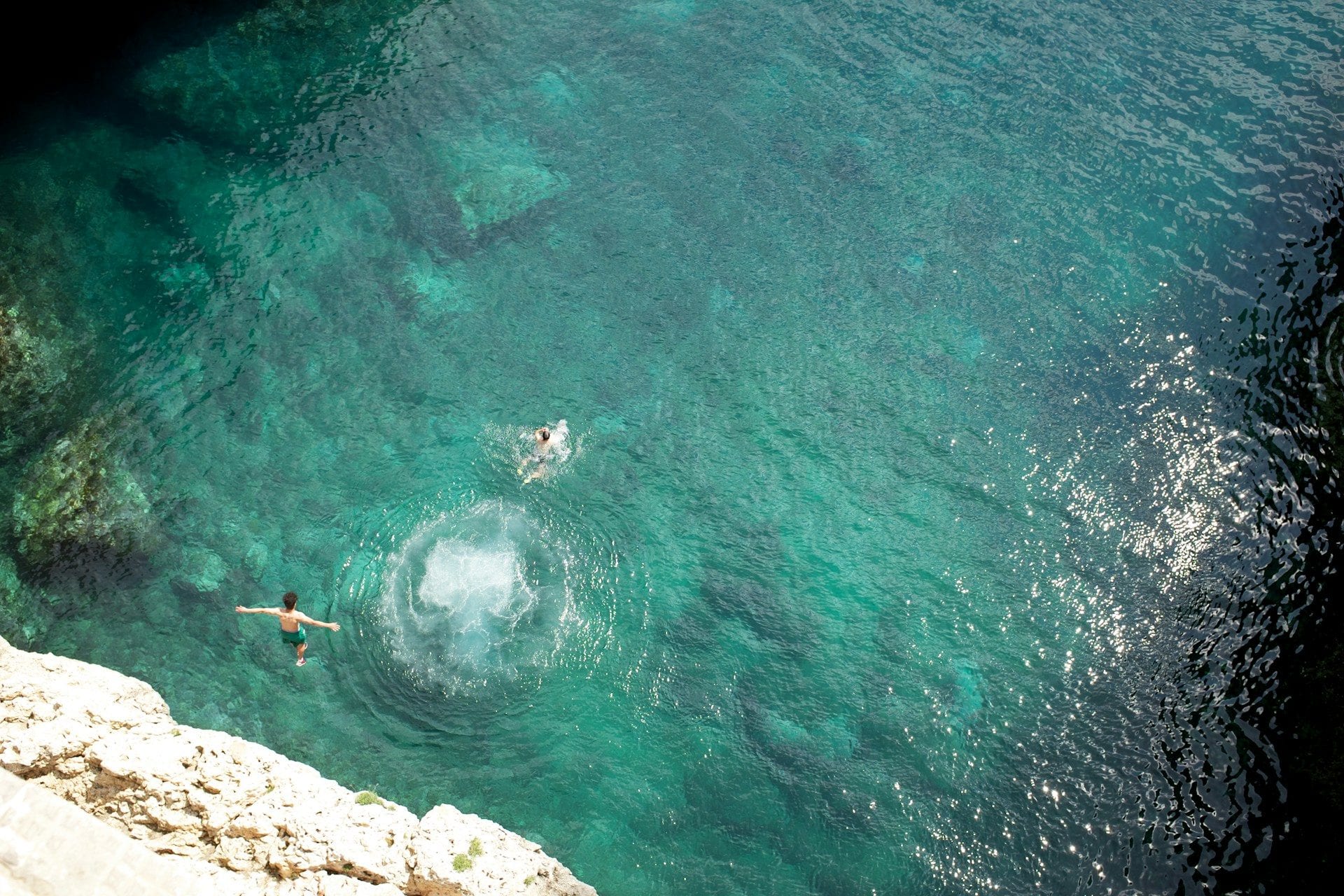 Two swimmers in crystal-clear turquoise waters along the Apulian coast